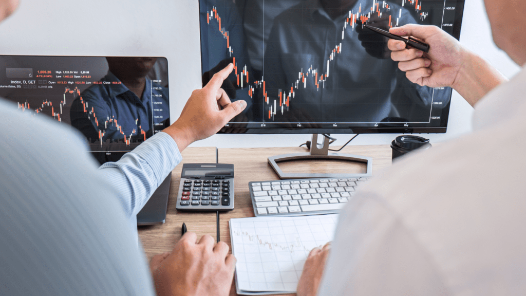 A person pointing at stock market on large screen