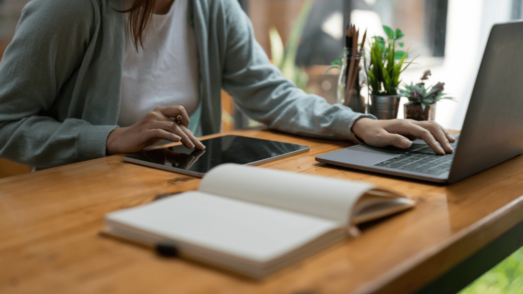 A person sitting at a table with a laptop and notebook