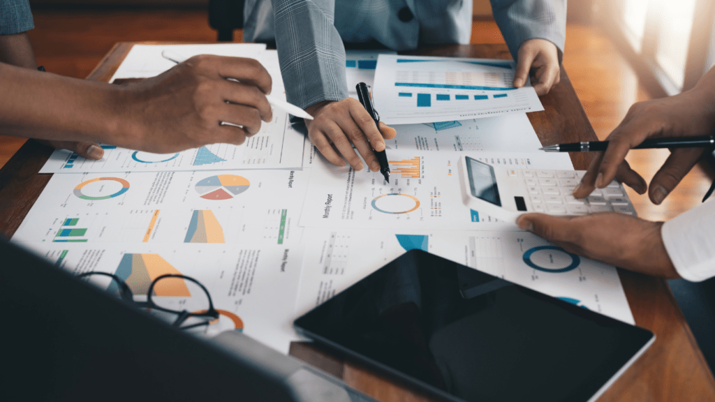 a group of business people at a table with graphs and papers