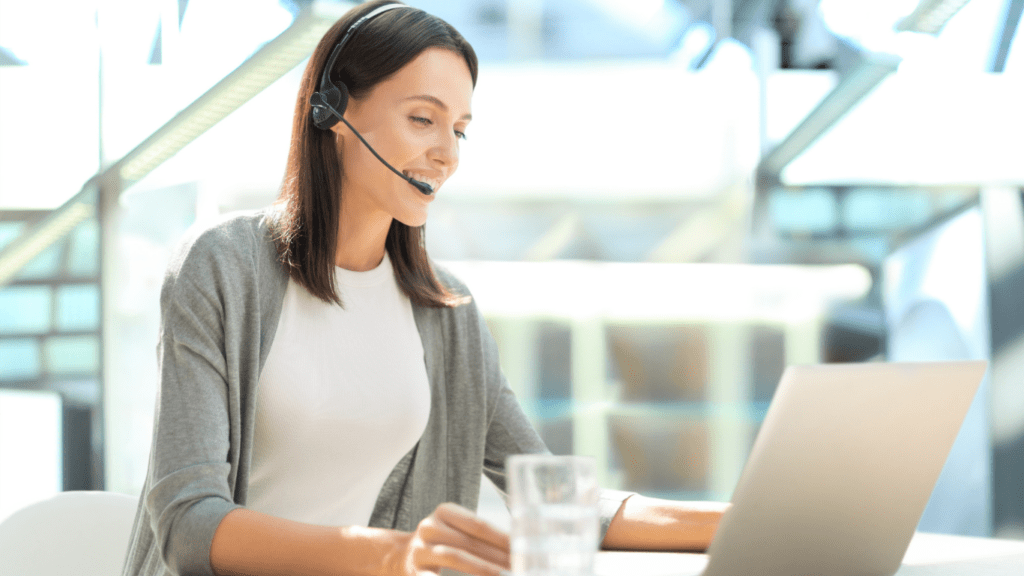 a person wearing a headset and sitting at a desk with a laptop