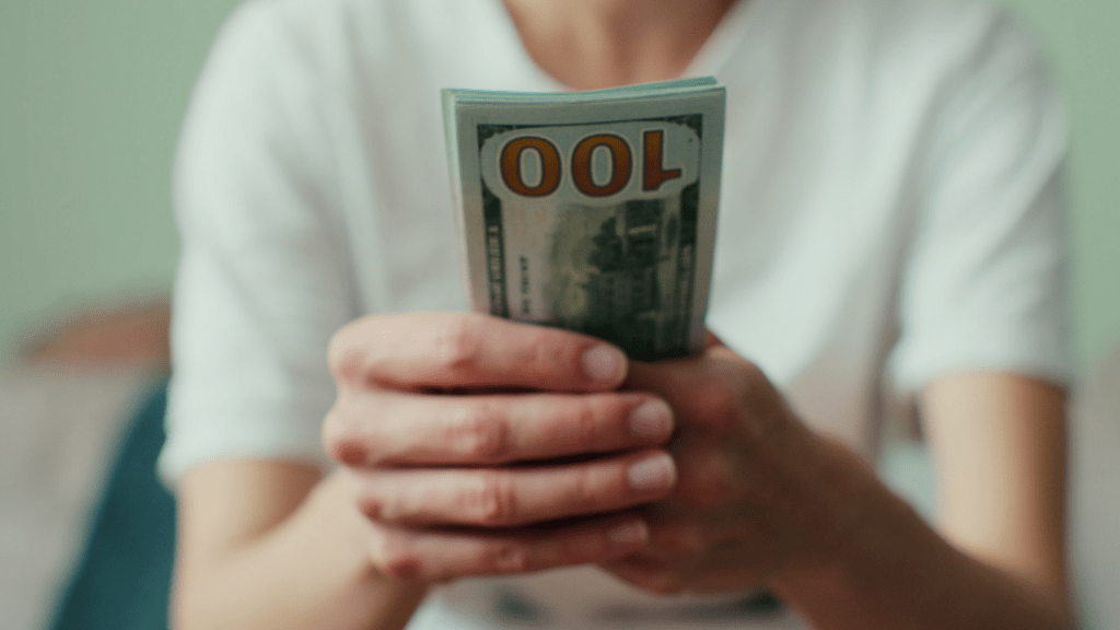 a person is counting money in front of a desk