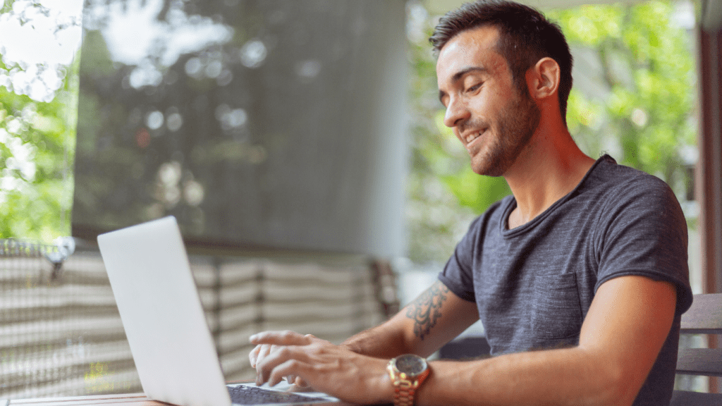 A smiling person working on a laptop