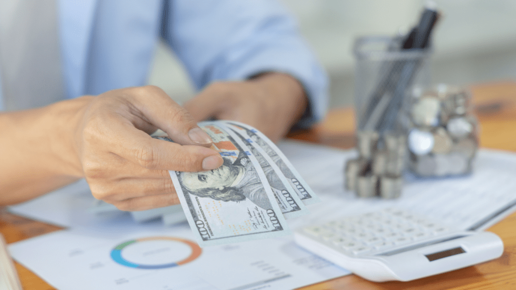 a person is counting money in front of a desk