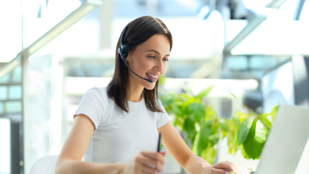 a person wearing a headset and sitting at a desk with a laptop