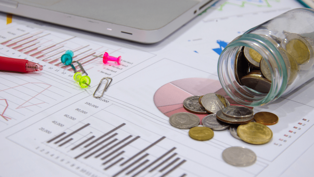 a stack of coins on top of a chart with a keyboard in the background